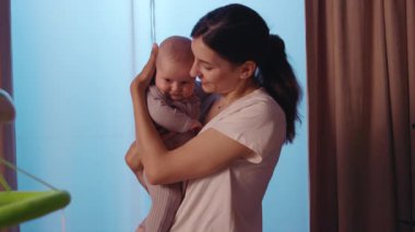 Genç mutlu anne kucağında ve yeni doğmuş bebeği okşuyor. Akşamları gülümsüyor. Apartmanda dikiliyorum. Annelik. Portre. Yavaş çekim