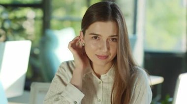 Gülümseyen çekici genç bir kadın kameraya bakıp güneş ışığı ofisinde mutlu hissederek başını çevirir. Başarılı bir iş kadını. Motive olmuş bir işveren. Ofis çalışanı. Yavaş çekim