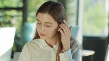 Saçlarına dokunan ve güneş ışığı ofisindeki kameraya bakan sevimli genç bir kadın. Başarılı bir iş kadını. Motive olmuş bir işveren. Gülümseyen işçi. Yavaş çekim