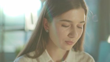 Güneş ışığı ofisinde başını çevirip kameraya bakan güzel bir genç kadının portresi. Başarılı bir iş kadını. Motive olmuş bir işveren. Bilgi İşlem. Yavaş çekim