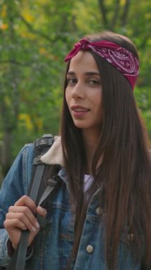 Şık ve kendine güvenen genç bir kadın şık bir bandana ve kot ceket giyerken açık havada poz veriyor.