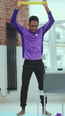 Bir adam evinde direniş bandını geriyor, aktif olarak fitness ve sağlıklı bir yaşam tarzını destekliyor.