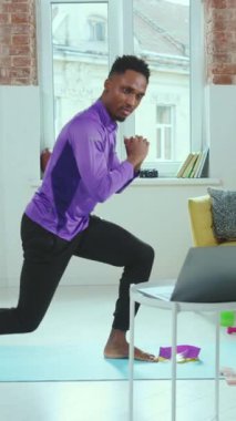 Adanmış bir fitness meraklısı şık spor giysileri giyerken aktif olarak ev antrenmanı yapıyor.