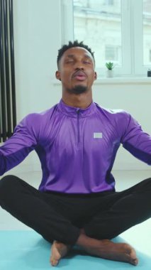 Bir adam yoga minderinin üzerinde otururken meditasyon yapıyor. Bu da hem rahatlamayı hem de farkındalığı arttırıyor.