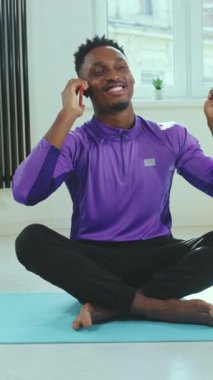 Neşeli bir adam mutlu bir şekilde farkındalık teknikleri uyguluyor. Işıkla dolu, aydınlık ve modern bir alanda yoga minderi üzerinde.