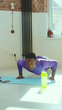 Formda bir genç adam aktif bir şekilde ev egzersizi yapıyor. Formunu ve zindeliğini gösteriyor.