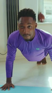 Şınav çekerken yoğun bir şekilde odaklanan bir adam fiziksel uygunluğunu parlak ve davetkar bir oturma odasında sergiliyor.