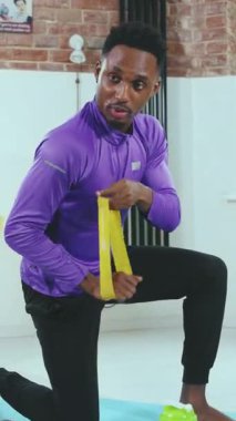 Odaklanmış bir adam direniş bandıyla diz çöker, fitness ve sağlık eğitimine bağlılığını gösterir.