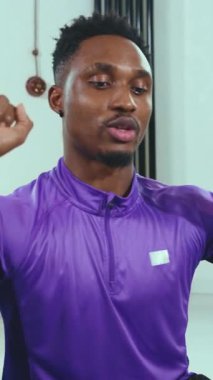 Kendini adamış bir erkek sporcu canlı mor bir idman kıyafeti giymiş, tamamen spor rutinine odaklanmış.