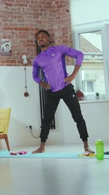 Atletik bir adam, rahat bir hava yayan şık ve çağdaş bir odada yoga pozu veriyor.