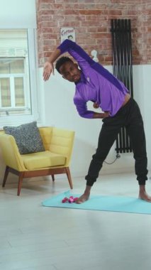 Genç bir adam, rahat bir ev ortamında kapsamlı ve odaklanmış bir egzersiz rutiniyle meşgul.