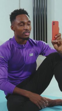 Egzersiz sırasında akıllı telefon kullanan atletik bir kişi, mevcut fitness eğilimlerini etkin bir şekilde gösterir