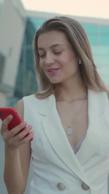 Canlı, genç bir kadın dışarıda vakit geçirmekten hoşlanır, şık beyaz bir elbise ve sevimli kulaklıklar giyer.