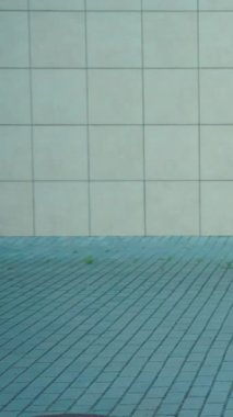 Altında desenli kaldırım taşları olan desenli beton bir duvarı gösteren minimalist bir perspektif.