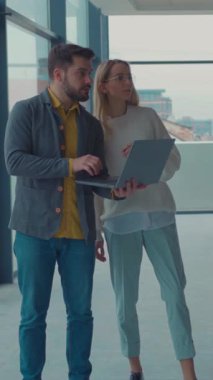 İki yetenekli profesyonel, şık bir ofis alanında dizüstü bilgisayar kullanırken aktif olarak ortak bir tartışmaya girişirler.