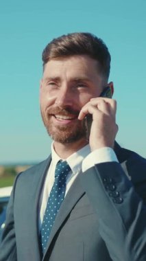 Takım elbiseli neşeli bir işadamı telefonda, profesyonelliğini ve kendine güvenini gösteriyor.