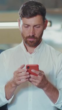 Akıllı telefon kullanan odaklanmış bir adam, çağdaş çalışma kültürünü ve modern teknoloji eğilimlerini sergiliyor.