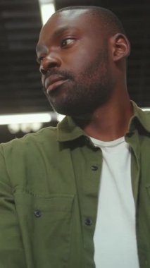 Düşünceli bir adam, modern bir şehir ortamında düşünceli bir şekilde yukarı bakar. Hayatı ve bakış açısını yansıtır.