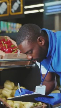 Kendini işine adamış ve çalışkan bir medya stokçusu yerel bir bakkalda taze ve renkli sebzeler düzenler.