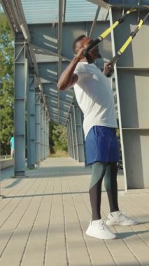 Formda bir adam açık hava süspansiyon eğitimi veriyor, fiziksel gücünü ve genel uygunluğunu gösteriyor.