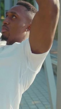 Formda ve sağlıklı bir genç adam modern bir şehir ortamında açık havada egzersiz yapıyor.