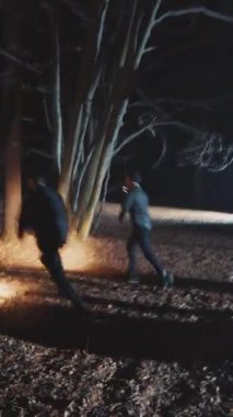 Gölgeli bir figür, ürkünç ay ışığında, ürkütücü ağaçlar ve kalın bir sis ile çevrili bir patikada dikkatle dolaşır.