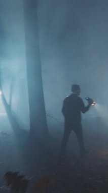Issız bir figür sisli bir ormanda yavaşça ilerler, uzak ve gizemli ışıklarla aydınlatılır.