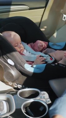 Neşeli küçük bir bebek rahat bir şekilde araba koltuğunda uzanıyor, mutlu bir şekilde bindikleri keyifli yolculuğun tadını çıkarıyor.