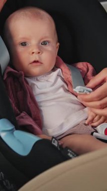 Araba koltuğuna rahatça oturmuş, aileler için güvenli bir yolculuk için gerekli eşyaları ve ipuçlarını sunan sevimli bir bebek.