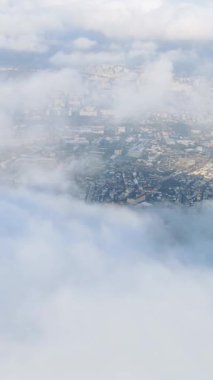 Yukarıdan gelen yumuşak, tüylü bulutlar tarafından kısmen gizlenmiş bir şehrin nefes kesici ve çarpıcı bir görüntüsü.