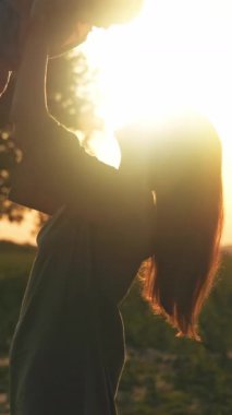 Gün batımında çocuğunu sevinçle kaldıran, sıcaklığı ve sevgiyi yakalayan büyüleyici güzellikteki bir ebeveyn silueti.