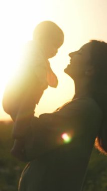 Yürek ısıtan bir siluet, sevgili bir annenin muhteşem bir gün batımına karşı bebeğini kucakladığını gösteriyor.