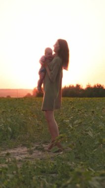 Huzurlu ve huzurlu bir an, sevgili bir annenin çarpıcı bir günbatımında kıymetli bebeğini kucaklamasını yakalar.