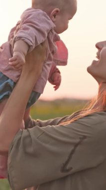 Sevgi dolu bir annenin, güzel bebeğini güzel bir günbatımına nazikçe sarktığını gösteren huzurlu ve yürekten bir görüntü.