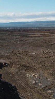 Göz kamaştırıcı bir panoramik manzara. Geniş, çorak bir arazi. Görkemli dağlar, berrak mavi bir gökyüzü altında.