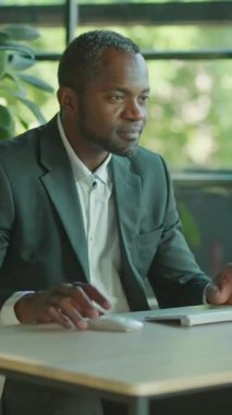 Kendini işine adamış ve işine odaklanmış bir işadamı, şık ve çağdaş bir ofis ortamında masasında özenle yazı yazıyor.