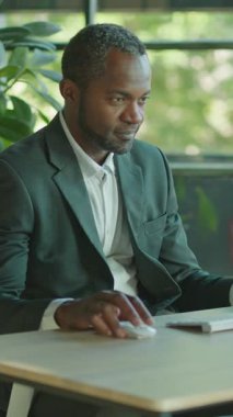 Takım elbise giymiş odaklanmış bir iş adamı modern ve çağdaş bir çalışma alanındaki bilgisayarı özenle kullanıyor.