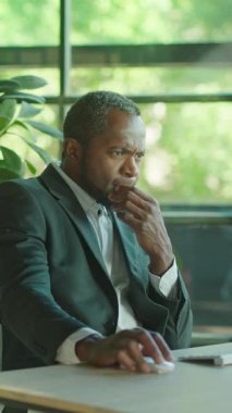 Takım elbise giymiş ciddi bir adam modern ofis ortamındaki özel görevine derinden odaklanır.