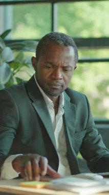 Çağdaş bir ofiste masa başında çalışan odaklanmış bir adam profesyonellik ve konsantrasyon yayıyor..