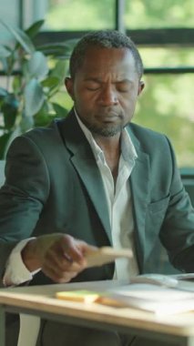 Akıllı takım elbiseli bir adam, modern ofis ortamında, düzenli bir masada tamamen işine dalmıştır.