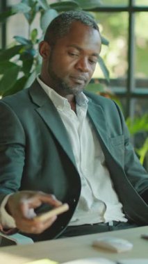 Düşünceli bir iş adamı, canlı bitkiler ve yemyeşil ile çevrili geniş ofisinde sessizce yansıtır.