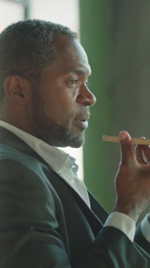 Takım elbiseli bir adam elinde bir pipet tutarken derin bir şekilde düşünür, modern bir ortamda düşünceli davranır..