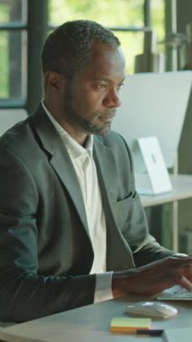 Modern ve şık bir ofis ortamında özenle dizüstü bilgisayar üzerinde çalışan kendini işine adamış ve odaklanmış bir profesyonel.