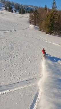 Yetenekli bir snowboardcu parlak güneşin altındaki pürüzsüz ve tozlu karda ustalıkla yol alır.