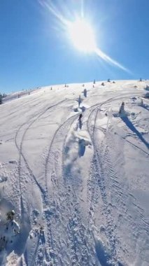 Bu resim, kışın güzelliğini vurgulayan canlı bir güneşin altında snowboard yapmanın heyecan verici deneyimini gösteriyor.