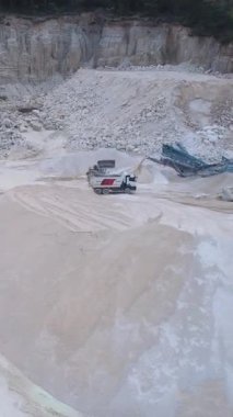 Kayalık arazide kumlu zeminin yanında ağır makinelerin bulunduğu geniş ve kapsamlı bir kazı alanı.