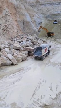 Geniş kazı alanını gösteren bir hava manzarası çeşitli makineler, kayalık arazi ve daha fazla