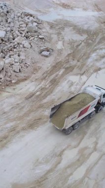 Bir çöp kamyonu kayalık bir taş ocağında ustalıkla yol alır, sert ve engebeli arazide malzeme taşır.