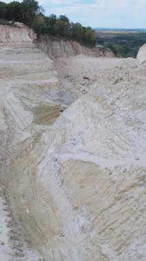 Kireç taşı ocağının çarpıcı manzarası, açık mavi gökyüzünün altında kayalık oluşumlarını sergiliyor.