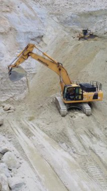 Kumlu bir arazide ustalıkla manevra yapan bir kazıcı, çeşitli inşaat projeleri için gerekli olduğunu kanıtlıyor.